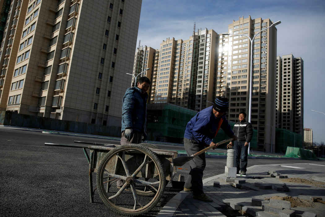  去年，工人们在北京郊区建设中的住宅小区附近工作。中国的房地产市场面临着堆积如山的债务，国有银行的低息贷款在许多行业制造了产能过剩。