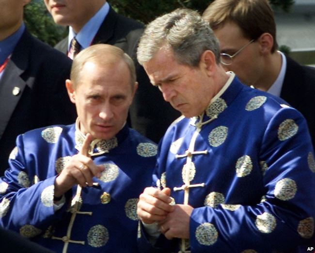 2001年10月21日 ，俄罗斯总统弗拉基米尔·普京和美国总统乔治·布什穿着中国传统丝绸外衣，在亚太经济合作组织（APEC）上海峰会上参加全家福合影时交谈。