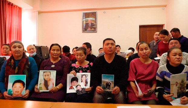 图为哈萨克人手持在新疆失踪亲人的照片。 （美联社）