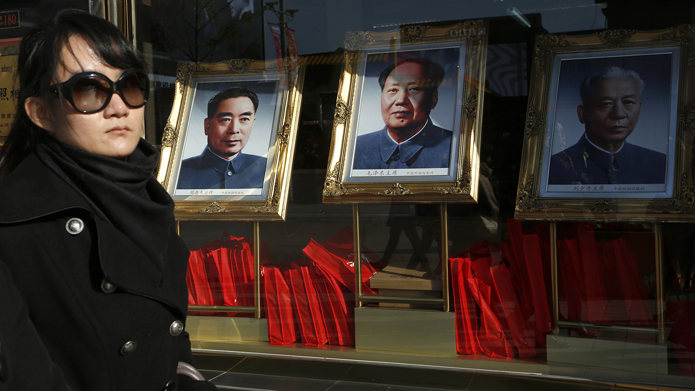 一名中国女子走过出售周恩来（左起）、毛泽东和刘少奇肖像的商场。（美联社）