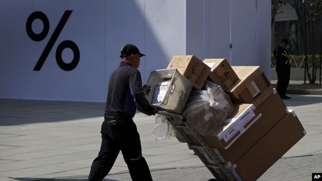 一名男子推着货物给北京一家商场送货。（2019年4月4日）