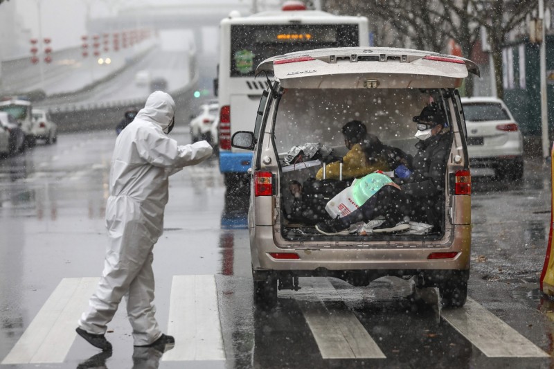 中国湖北省饱受武汉肺炎疫情肆虐，时序已经进入新春，却仍深陷在寒风中；图为15日武汉市某家指定收治感染者的医院，工作人员身穿全套防护衣在雪中接收患者。（美联社）