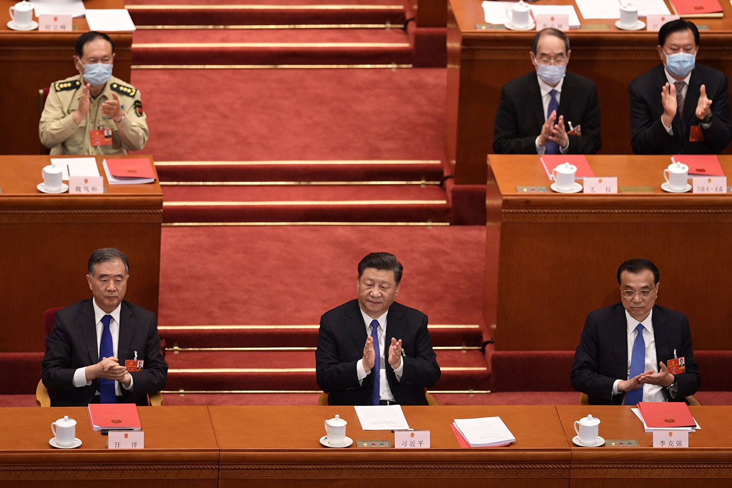 2020年5月28日，在北京人民大会堂举行的全国人民代表大会，习近平（中），李克强（右）和汪洋（左）对起草香港安全法的提案进行投票后。（法新社）