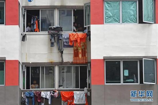 4月6日，在新加坡西雅卓源外籍劳工宿舍，几名外籍劳工从宿舍楼中向外张望。