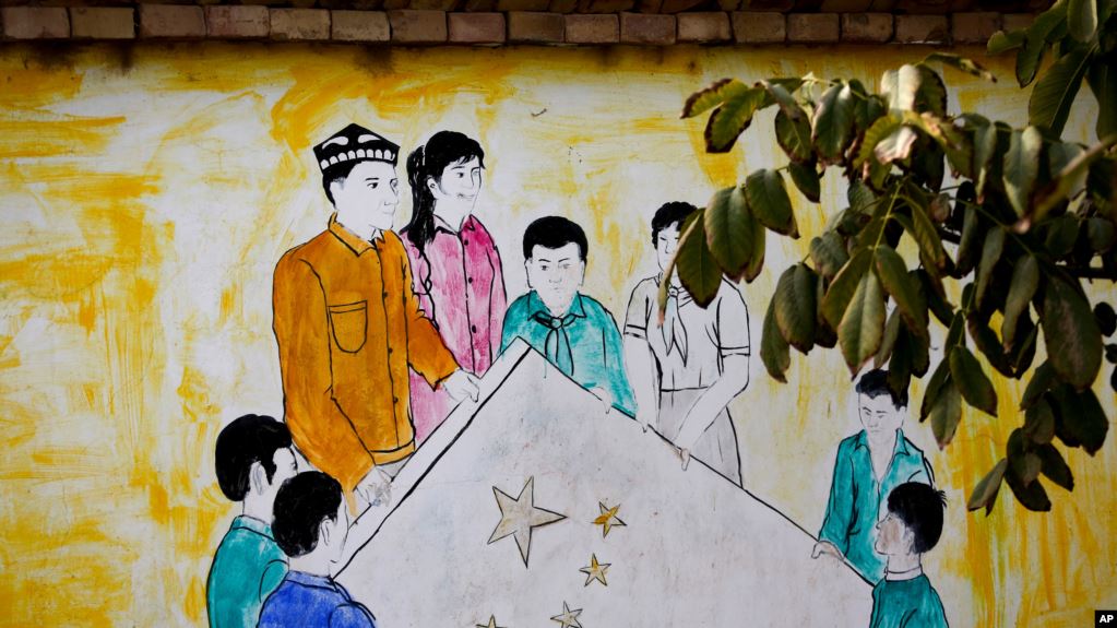 资料照片: 新疆和田团结新村一所住宅内显示维吾尔和汉族男女共持五星旗的壁画。(2018年9月20日)