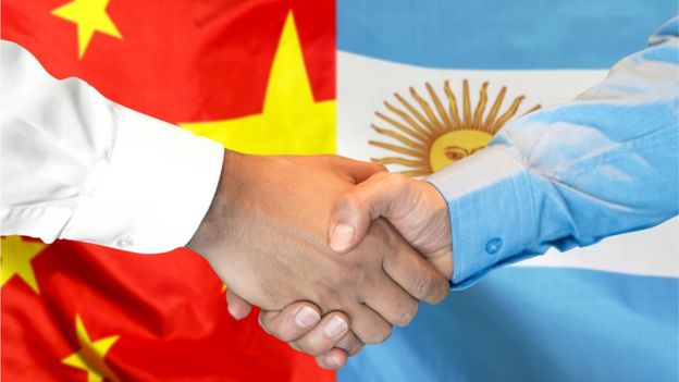 Apretón de manos frente a las banderas de China y Argentina
