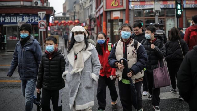北京前门商圈一群戴着口罩的男女老幼过马路（28/2/2021）