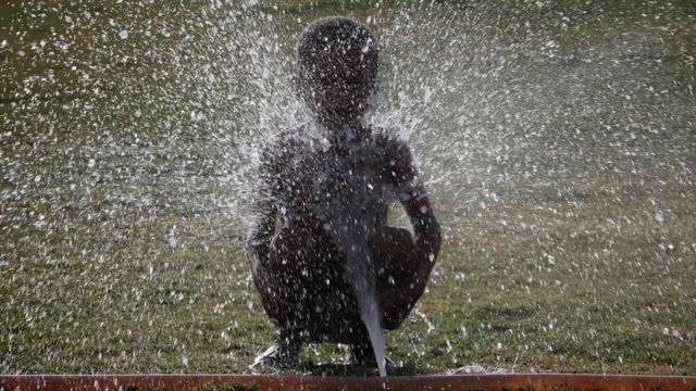 A child is sprayed with water from an irrigation hose