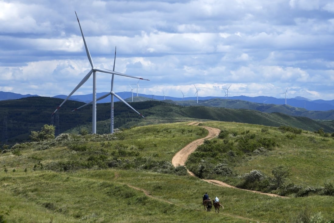 Tourists ride horses near wind turbines on the grassland in Zhangbei county, Hebei province, on August 15. China, currently the top emitter of greenhouse gases in the world, aims to reach net zero by 2060, requiring significant slashing of emissions. Photo: AP