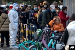 北京居民2022年11月17日冒着刺骨寒风在一个检测站外排长队等候新冠核酸检测。
