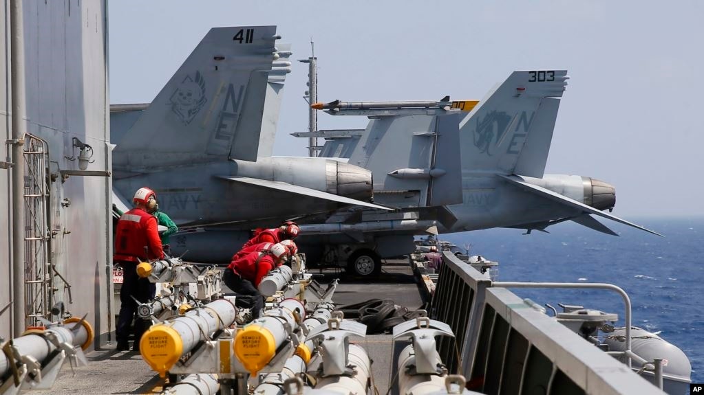 2017年3月3日在南中国海例行巡航前，美国航母卡尔·文森号上的海军人员准备为F-18战斗机加装导弹。