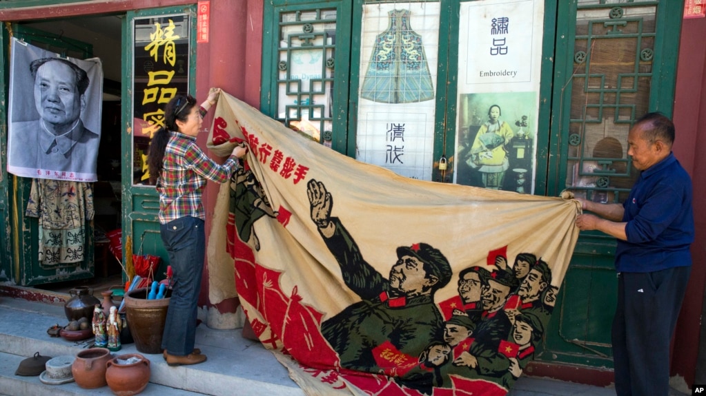 北京商贩正在展示一面画有中国前领导人毛泽东在文革时期的宣传旗。（2016年5月16日）