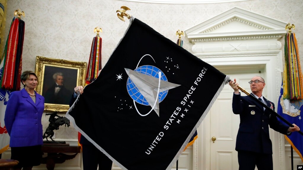 在白宫椭圆形办公室，空军部长芭芭拉·巴雷特(左)注释着总军士长罗杰·陶伯曼展示美国太空军的军旗。(2020年5月15日)