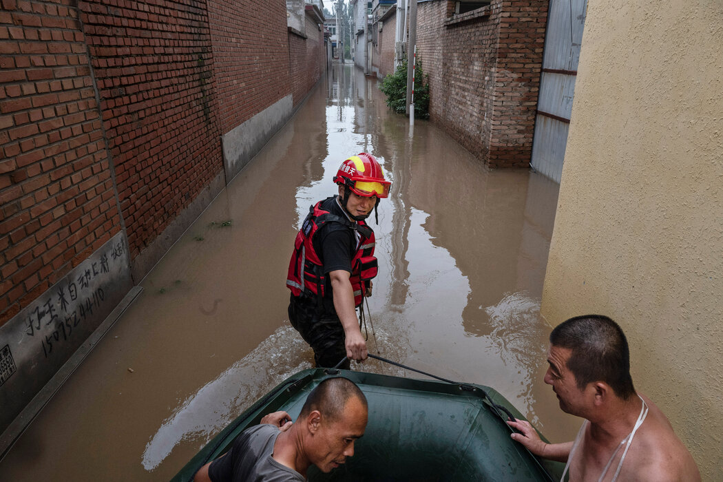 周四，一名救援人员在涿州附近拉着一艘载有居民的船只。
