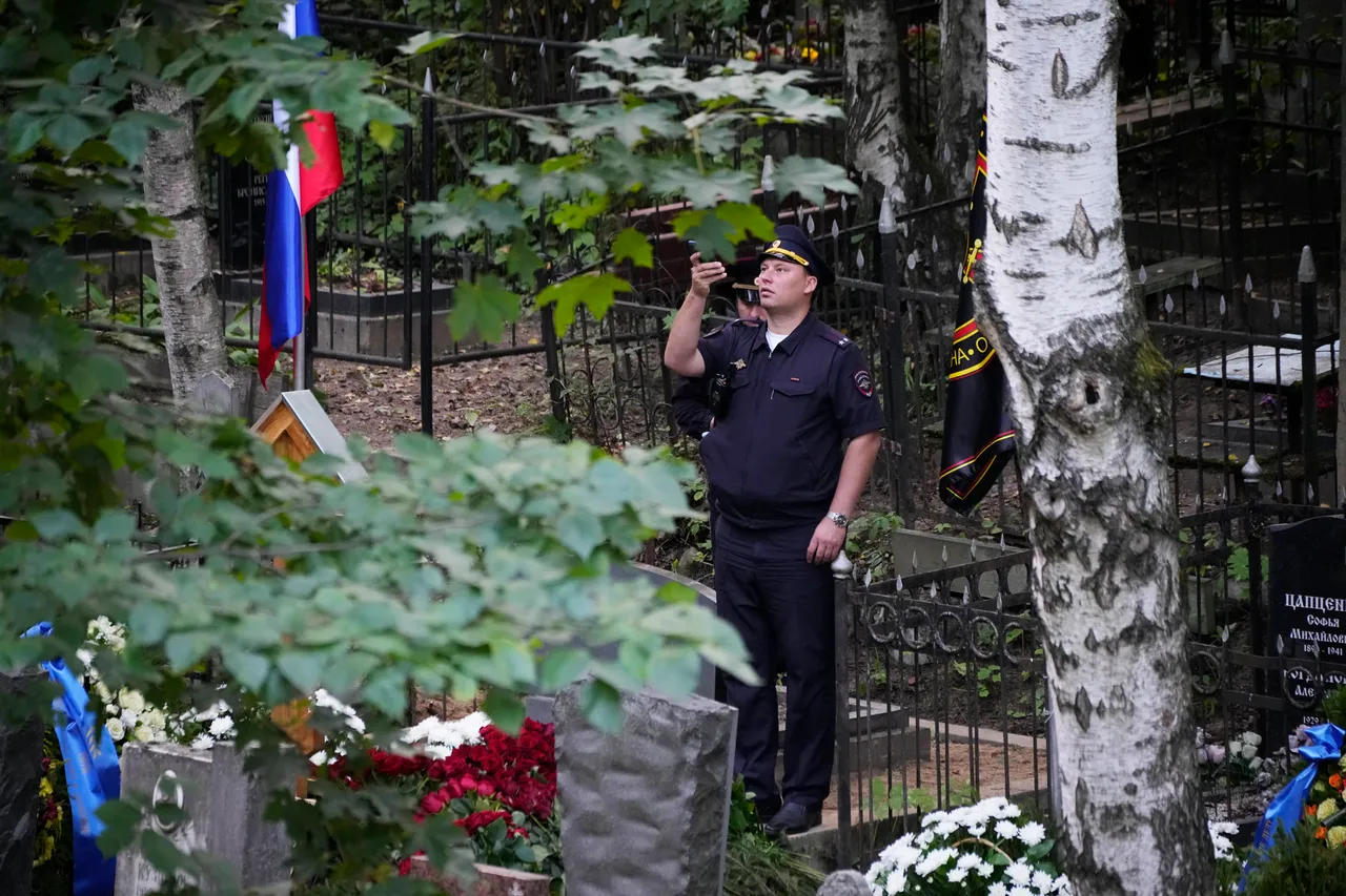 一名警員對著普里格津的墳墓拍照。美聯社