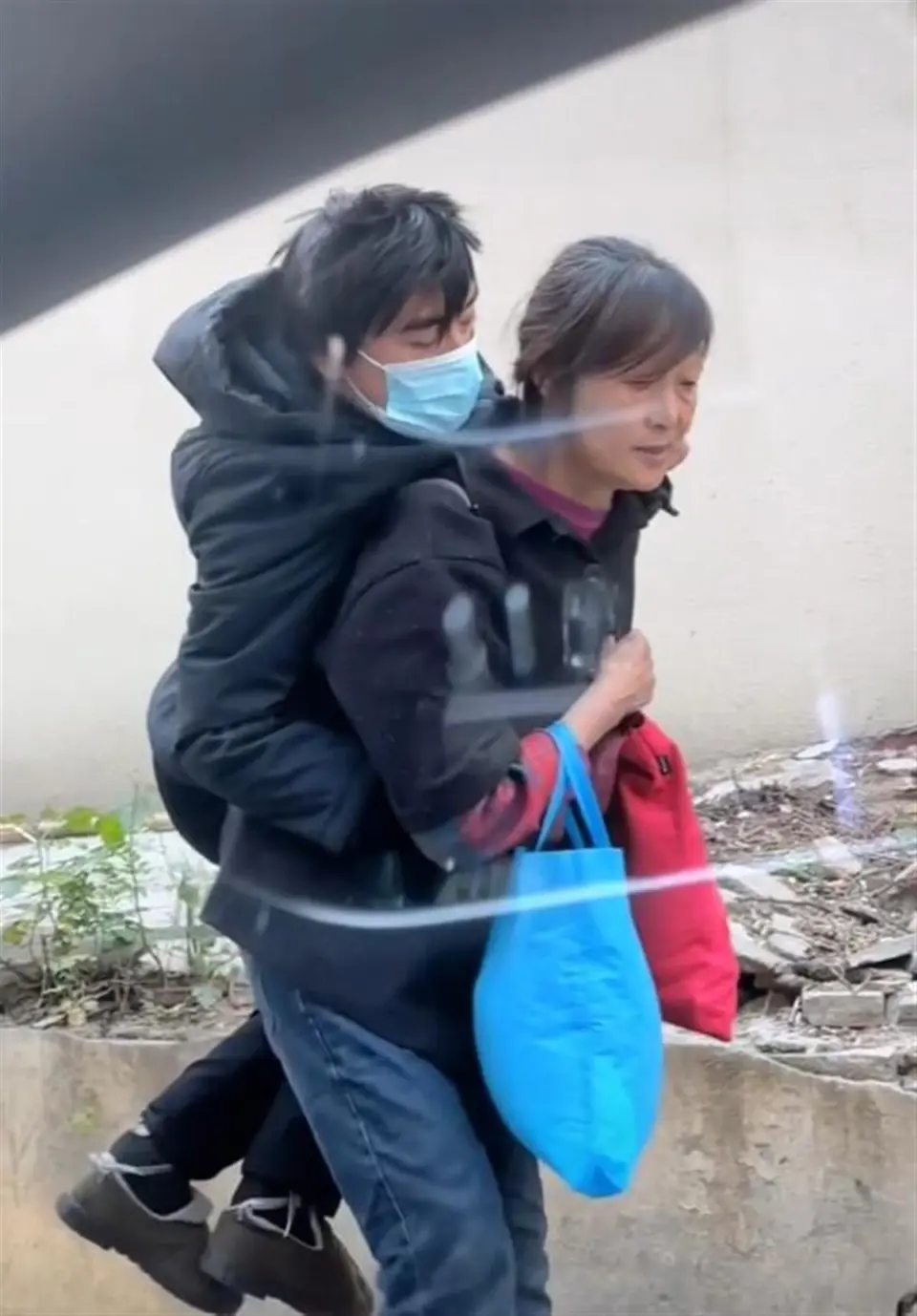 南京一年迈母亲背着成年儿子艰难行走？官方回应