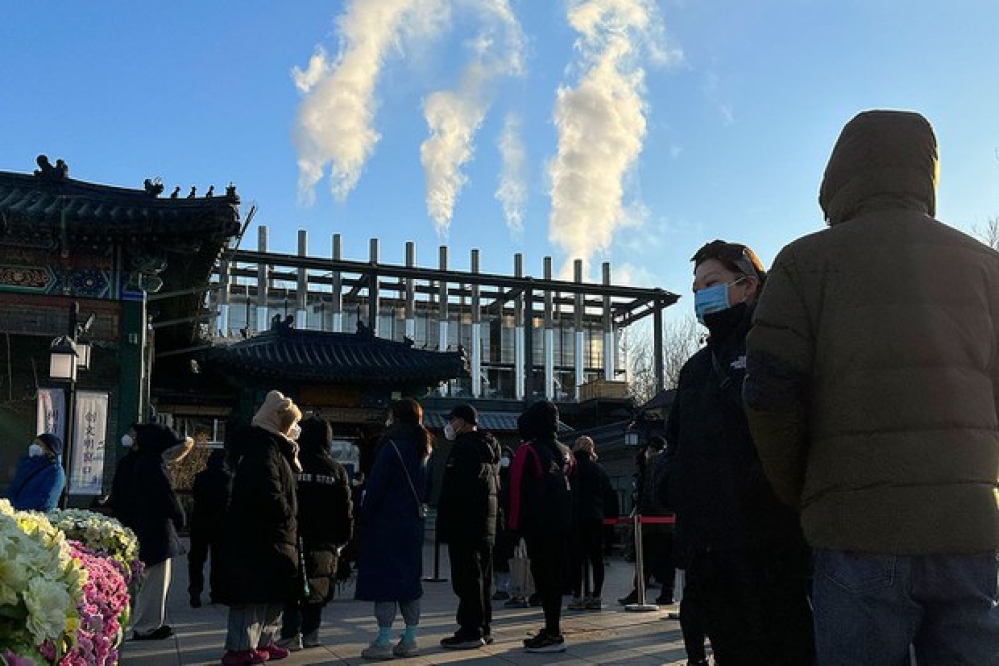 2022年12月31日，北京火葬場的煙囪冒出濃煙，送葬者站在火葬場外。（美聯社）