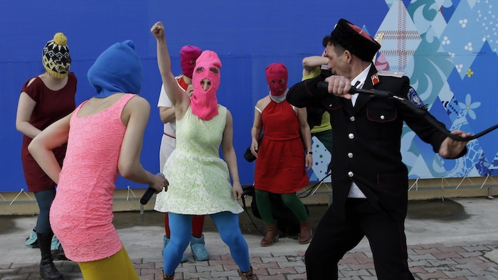 Members of the punk group Pussy Riot, including Nadezhda Tolokonnikova in the blue balaclava and Maria Alekhina in the pink balaclava, are attacked by Cossack militia in Sochi, Russia, on Wednesday, Feb. 19, 2014. The group had gathered in a downtown Sochi restaurant, about 30km (21miles) from where the Winter Olympics are being held. They ran out of the restaurant wearing brightly colored clothes and ski masks and were set upon by about a dozen Cossacks, who are used by police authorities in R