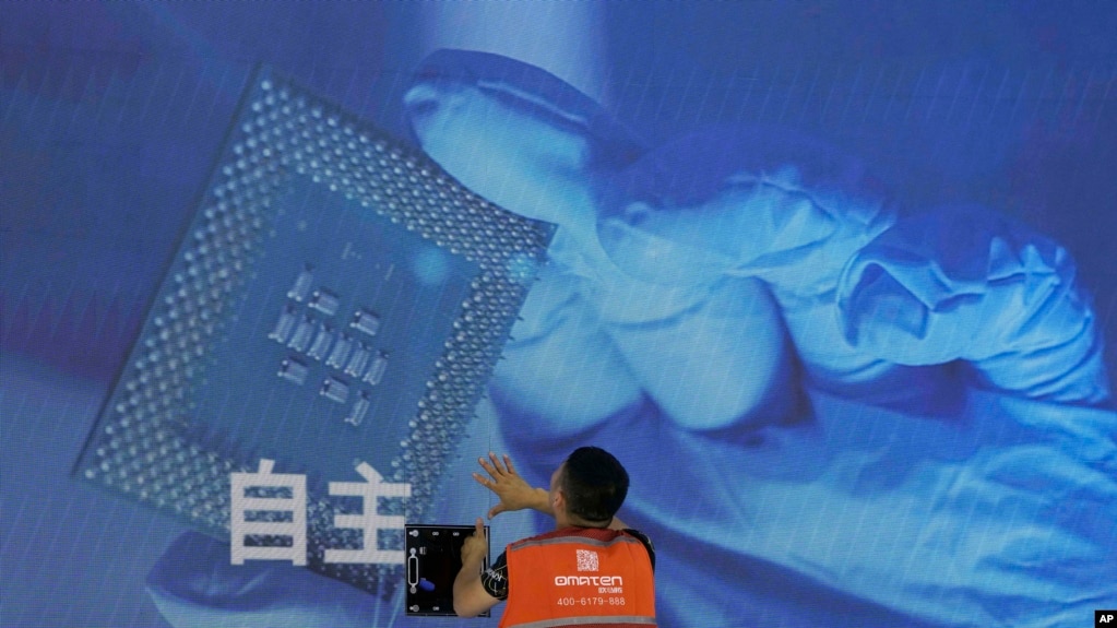 一名工人在上海举办的世界人工智能大会上检查中国科技公司中科曙光展示的芯片和“自主”
字样的屏幕。（2023年7月5日）