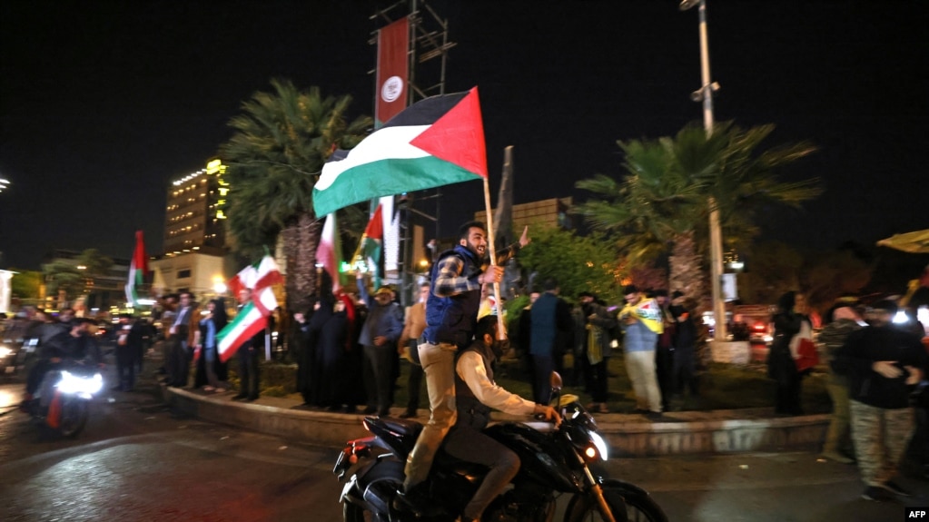 伊朗对以色列发动空袭后，示威者在伊朗首都德黑兰挥舞伊朗国旗游行。（2024年4月14日）